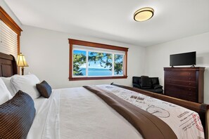 Habitación de hotel con cama, televisor, escritorio y ventana con vista al mar.