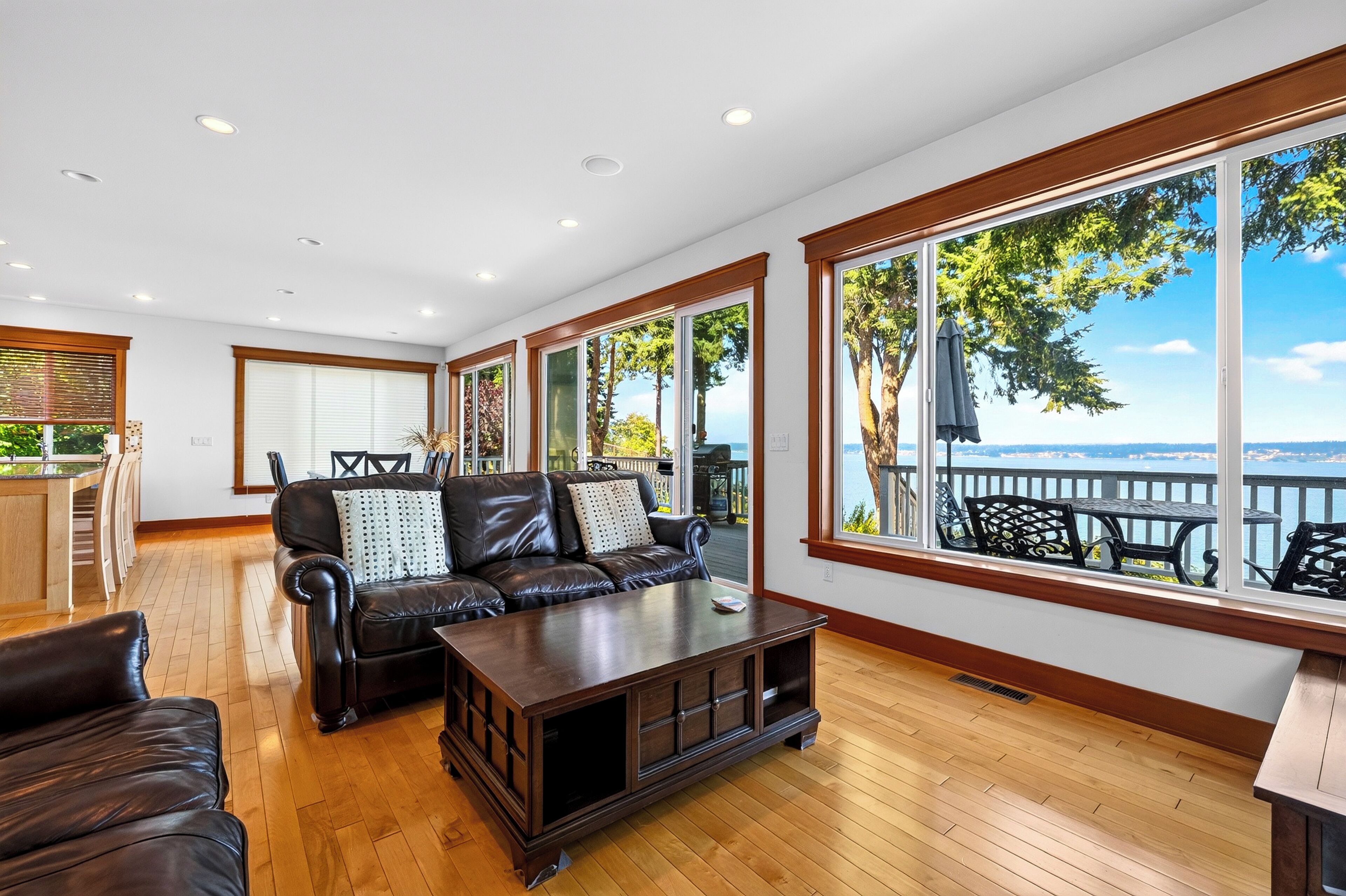 Amplia sala de estar con un sofá de cuero, una mesa de centro de madera y ventanas amplias con vistas al exterior.