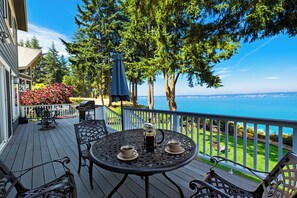 Eine Terrasse mit Sitzgelegenheit, Grill und Meerblick.