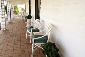 Relax in a serene outdoor seating area with wicker chairs and lush greenery.