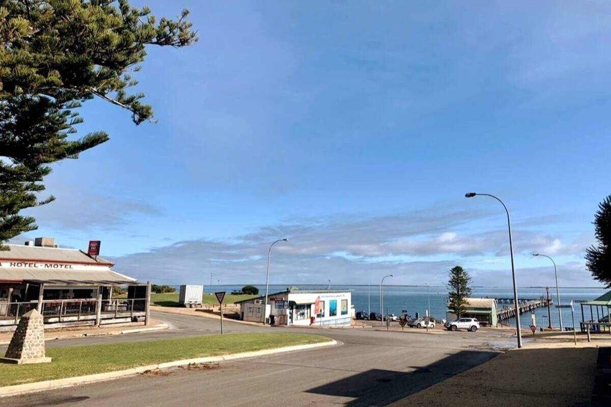 Um hotel à beira-mar com vista para o oceano, um pequeno edifício anexo e um cais que se estende para a água.