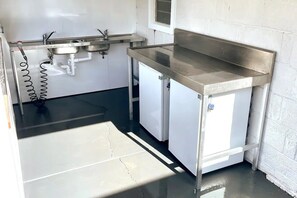 Functional kitchen with stainless steel countertops, two sinks, and a compact refrigerator.