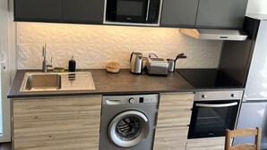 Cocina compacta equipada con lavadora integrada, microondas y tostadora.