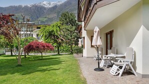 Une cour d’hôtel avec des espaces de repos en plein air, un jardin et une vue sur les montagnes en arrière-plan.