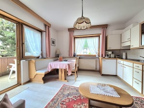 Una cocina pequeña con comedor, un radiador y una ventana con cortinas.