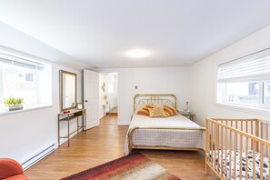 A bedroom with a bed, a crib, a console table, a mirror, and a window. - Spacious Family Home central to Squamish (Squamish)