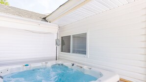 Ein Whirlpool mit Bedienfeld, ein Fenster mit Jalousien und eine weiße Außenwand.