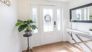 Ein Flur mit einer weißen Tür, einem Blumentopf, einem Spiegel und einer Treppe.