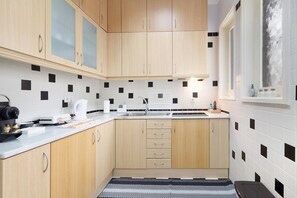 A modern kitchen with wooden cabinets, a black and white tiled backsplash, a built-in oven, and a window with a view.