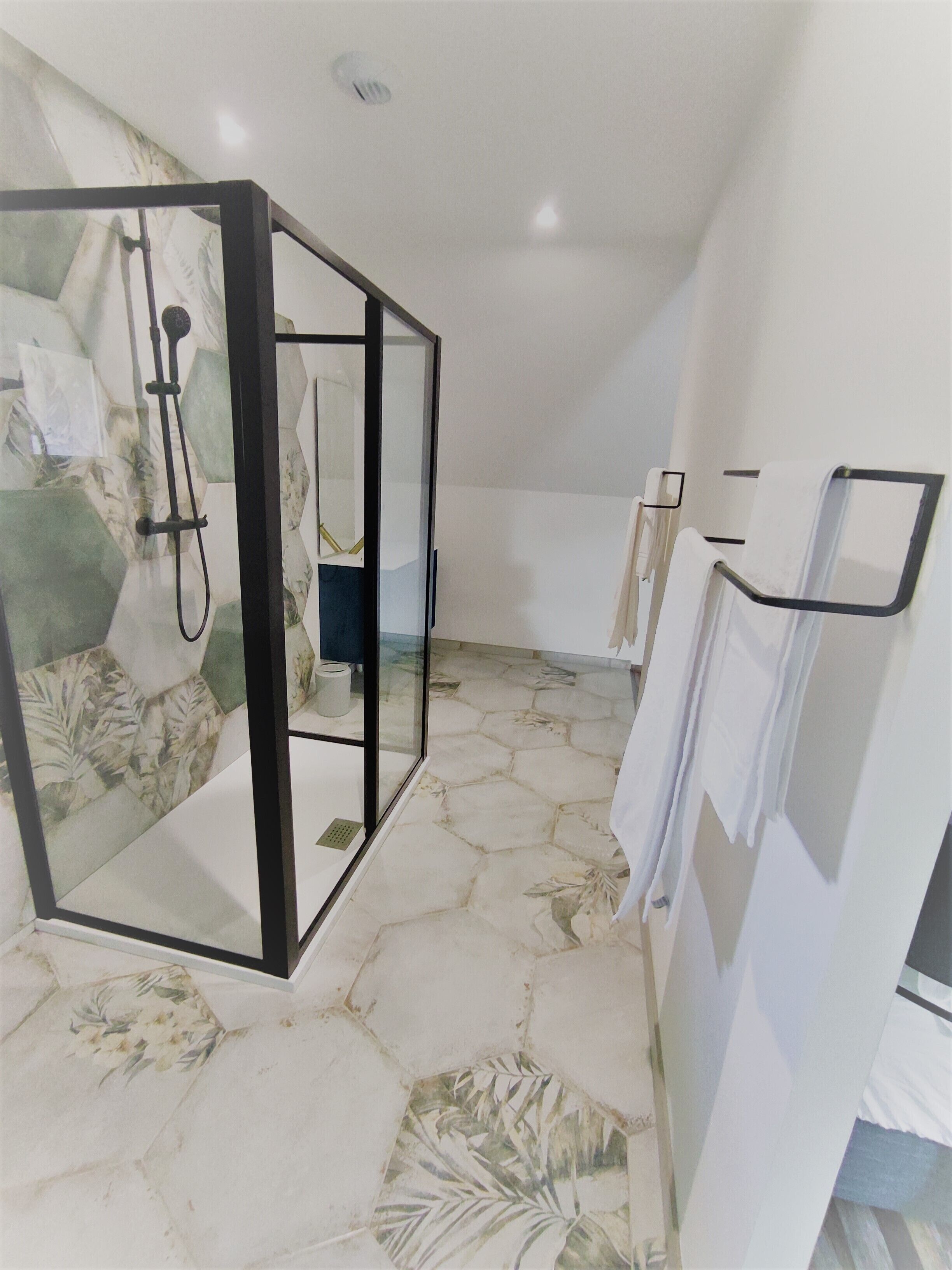 A bathroom with a shower enclosure, a toilet, and a towel rack.