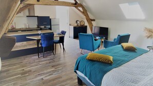 An attic bedroom with a bed, chairs, and a desk.