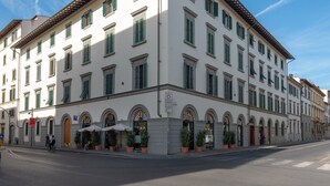 A multi-story building with a row of shops on the ground floor, including a restaurant with outdoor seating. - Holiday Apartment "Romantic Suite Home" with Balcony & Wi-Fi (Firenze)