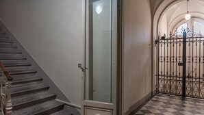 A staircase with a wooden handrail, a glass door with a circular handle, and a checkered floor. - Holiday Apartment "Romantic Suite Home" with Balcony & Wi-Fi (Firenze)