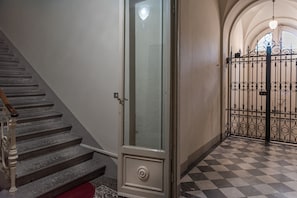 A staircase with a wooden handrail, a glass door with a circular handle, and a checkered floor.