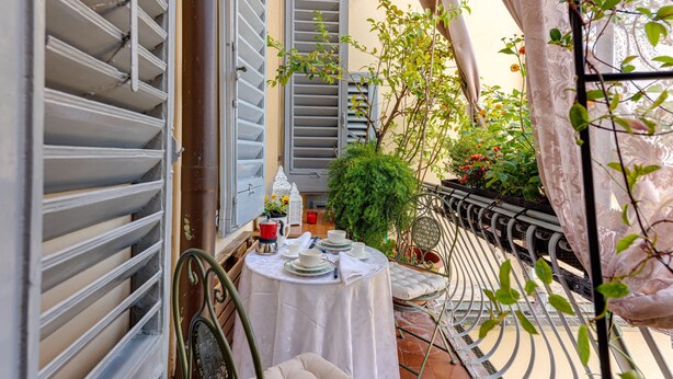 A small outdoor balcony with a table set for two, a potted plant, and a metal railing. - Holiday Apartment "Romantic Suite Home" with Balcony & Wi-Fi (Firenze)