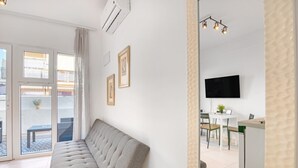 A modern living room with a sofa, a flat-screen TV, a dining area, and a balcony. - Holiday Apartment "Soleole1" with Shared Terrace & Wi-Fi (Gandia)