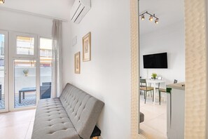 Un soggiorno moderno con divano, televisore piatto, zona pranzo e balcone.