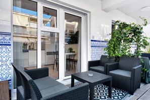 Un patio con mobili in vimini, una porta vetrata che dà su un balcone e un muro decorato.
