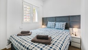 A bedroom with a bed, a nightstand, a window, and a view of buildings outside. - Holiday Apartment "Soleole8" with Shared Terrace, A/C & Wi-Fi (Gandia)