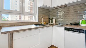 A kitchen with white cabinets, a window with a view of buildings, a tiled backsplash, and a dishwasher. - Holiday Apartment "Soleole8" with Shared Terrace, A/C & Wi-Fi (Gandia)