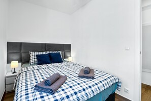 A bedroom with a bed, pillows, a nightstand, and a lamp.