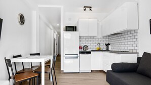 Une cuisine moderne avec des meubles blancs, un four à micro-ondes et une machine à café.