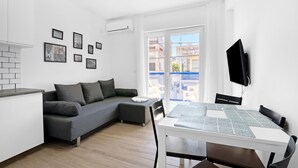 Un salon moderne avec un canapé, une table à manger et un téléviseur.