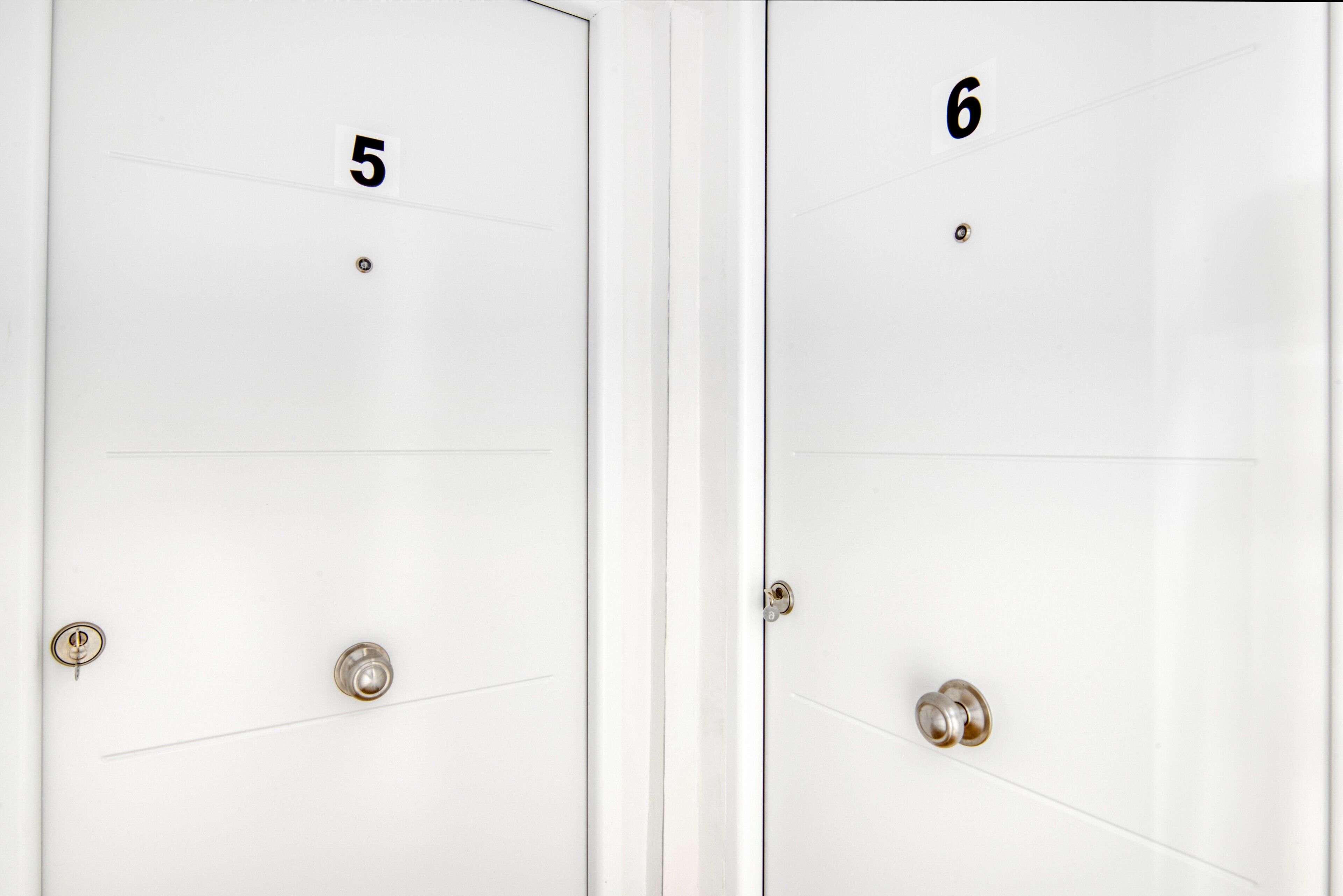 Two white doors with numbers 5 and 6, each with a keyhole and a door handle.