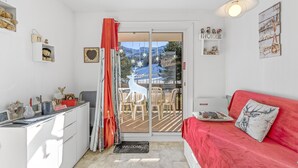 A room with a red sofa, a white cabinet, a glass door leading outside, and a ceiling light. - Apartment 'Superdévoluy Les Issarts' with Mountain View, Balcony and Wi-Fi (Superdevoluy)