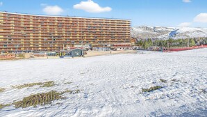 A large, multi-story hotel with balconies, a beach area, and mountains in the background. - Apartment 'Superdévoluy Les Issarts' with Mountain View, Balcony and Wi-Fi (Superdevoluy)
