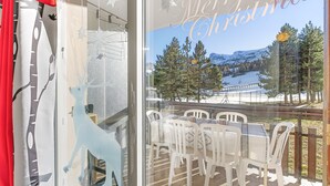 A room with a glass wall, a table with chairs, and a view of a snowy landscape. - Apartment 'Superdévoluy Les Issarts' with Mountain View, Balcony and Wi-Fi (Superdevoluy)