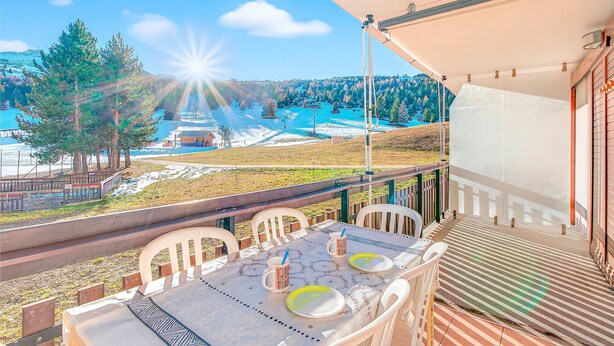 A balcony with a table set for two, overlooking a snowy landscape and a clear blue sky. - Apartment 'Superdévoluy Les Issarts' with Mountain View, Balcony and Wi-Fi (Superdevoluy)