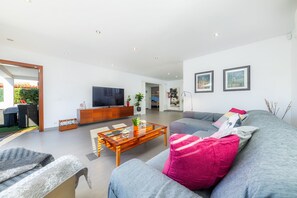 Una sala de estar moderna con un sofá, una mesa de centro, un televisor y un amplio ventanal.
