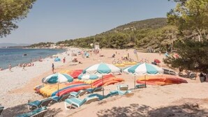 Une plage avec des parasols, des chaises et des gens.