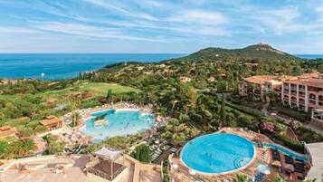 Un complexe hôtelier doté de plusieurs piscines, d’une végétation luxuriante et offrant une vue sur la mer.