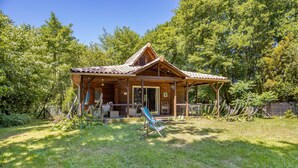 Une cabane en bois dotée d’un porche, entourée d’une végétation luxuriante.