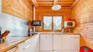 Une cuisine de taille réduite avec des murs en bois, un four à micro-ondes, un évier et un lave-vaisselle.