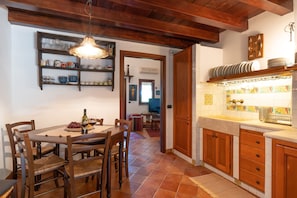 Un'area pranzo con un tavolo e sedie in legno, un lampadario e una cucina con mobili in legno e una parete rivestita di piastrelle.