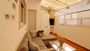 A cozy living area with a sofa, a small table, and a stone fireplace. - Apartment 'Âncora B' with Private Terrace (Monte Gordo)