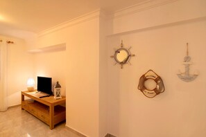 Une pièce avec un meuble TV en bois, un miroir et des décorations murales sur le thème de la marine.