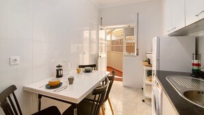 A compact kitchen with white cabinets, a sink, and a dining area with chairs and a table. - Apartment 'Âncora B' with Private Terrace (Monte Gordo)