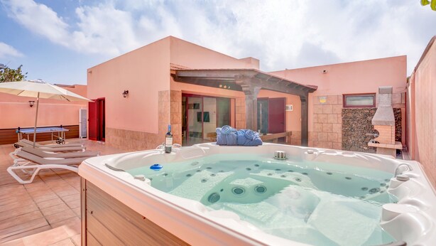 A spa area with a hot tub, lounge chairs, and a covered patio. - Villa Malva: Private Jacuzzi, Ping Pong & Relaxation in Corralejo (Corralejo)