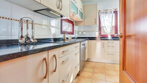A kitchen with white cabinets, a black countertop, and a tiled floor. - Villa Malva: Private Jacuzzi, Ping Pong & Relaxation in Corralejo (Corralejo)