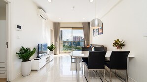 A modern dining area with a white table, black chairs, and a city view through large windows.