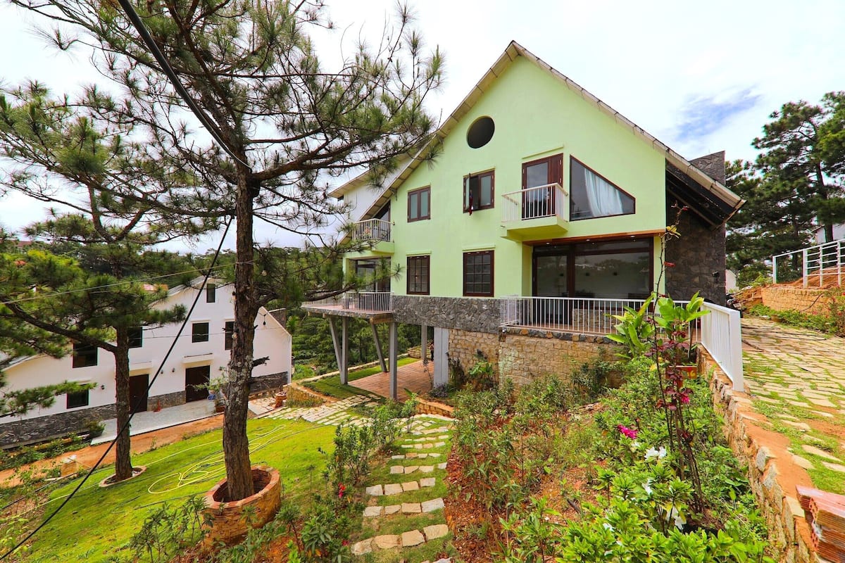 A two-story house with a green facade, stone accents, and a balcony.