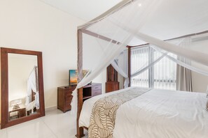 A bedroom with a canopy bed, a large mirror, a wooden dresser, and a painting on the wall. - Luxurious, Spacious and Chic two bedroom villa in excellent location in Seminyak (Bali)