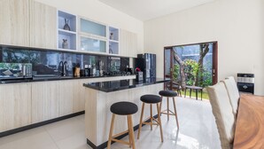 Eine moderne Küche mit Marmorarbeitsplatte, Holzschränken und einem Essbereich mit Holztisch und Barhocker.