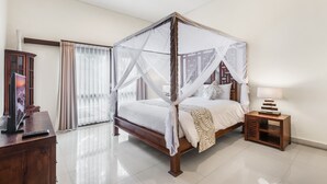 A bedroom with a four-poster bed, a bedside table, a TV, and a large window with curtains. - Luxurious, Spacious and Chic two bedroom villa in excellent location in Seminyak (Bali)