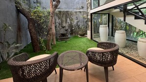 Eine Terrasse mit Korbstühlen, einem kleinen Rasen und einer Steinmauer.