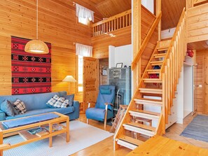 Ein Holzinnenraum mit einer Couch, einem Sessel und einer Treppe.